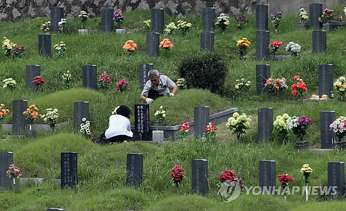到釜山永樂公園掃墓的人絡(luò)繹不絕，圖為一對老夫婦在整理墓地。（圖片來源：韓聯(lián)社）