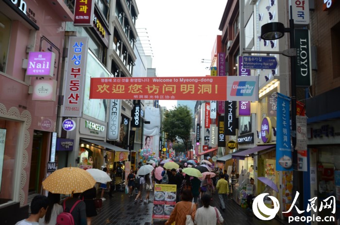 國慶黃金周期間，冒雨在明洞街頭購物的中國游客們。（攝影：裴埈基）