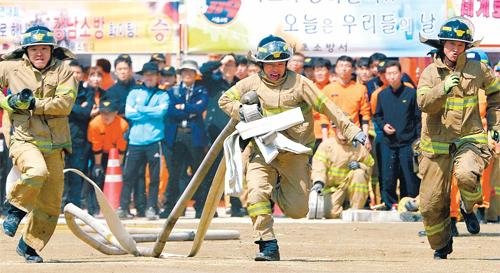 參賽的消防員們迅速接好消防水帶、水槍，并鋪開水帶奔向起火部位。