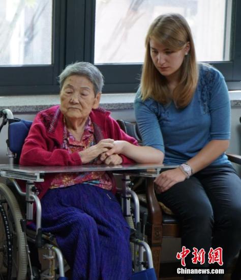 一名昔日被日軍強(qiáng)征的“慰安婦”在接受采訪過程中一直握緊著身旁外國志愿者的手。 中新社發(fā) 吳旭 攝