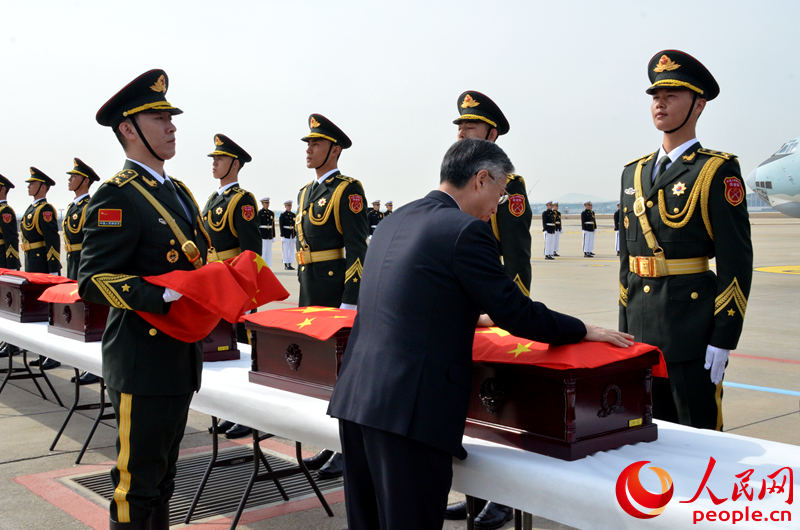 中國駐韓國大使邱國洪為中國人民志愿軍烈士遺骸棺槨覆蓋國旗。夏雪 攝