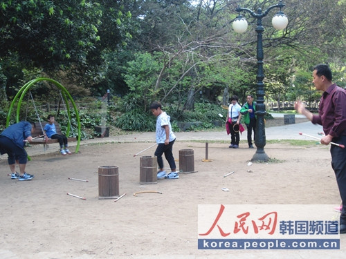 韓國傳統(tǒng)游戲之投壺圖片攝于濟州島天地淵瀑布景區(qū)內(nèi)，游人在投壺